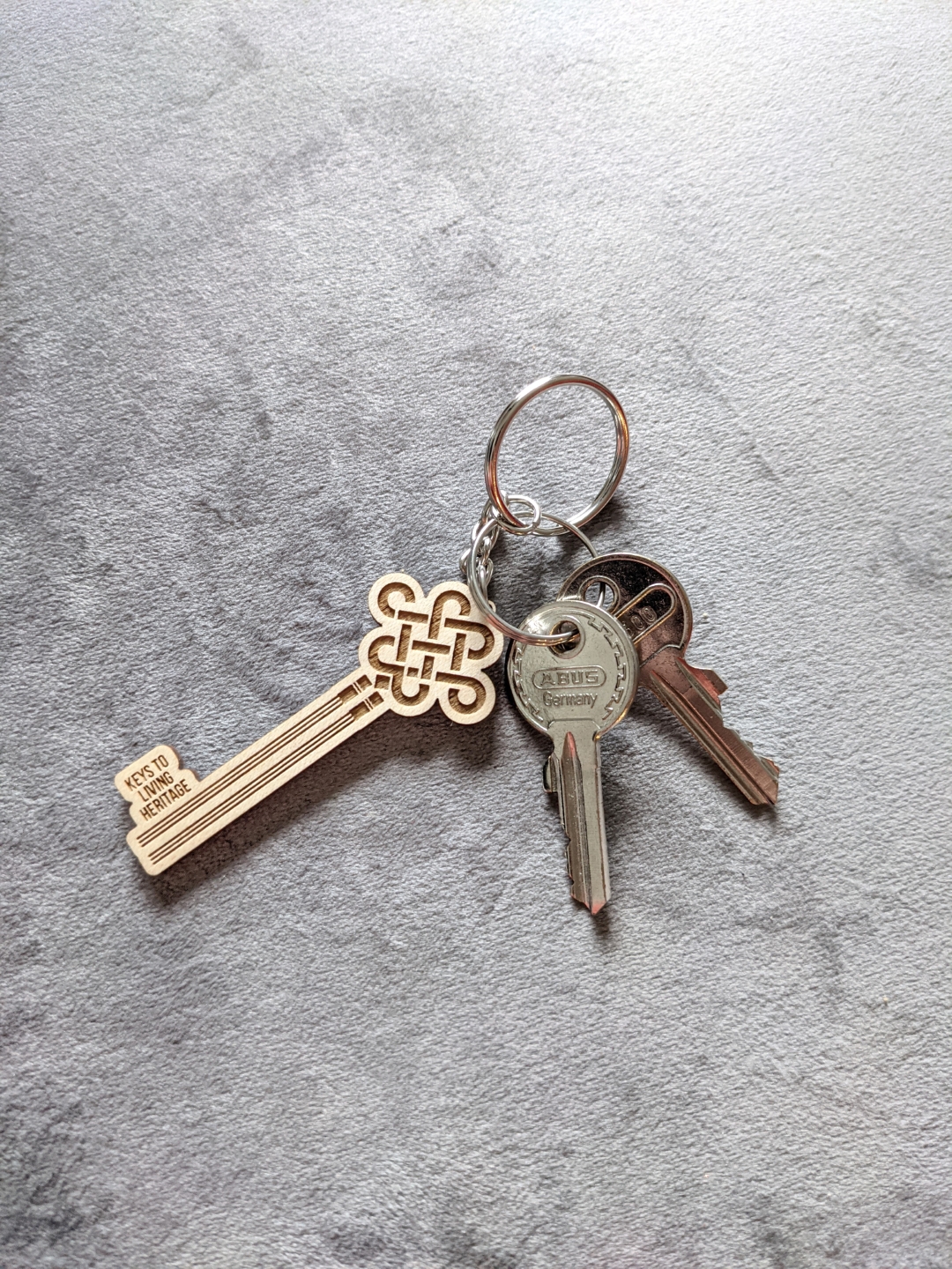 Keychain with two metal keys and a wooden decorative key labeled Keys to Living Heritage.