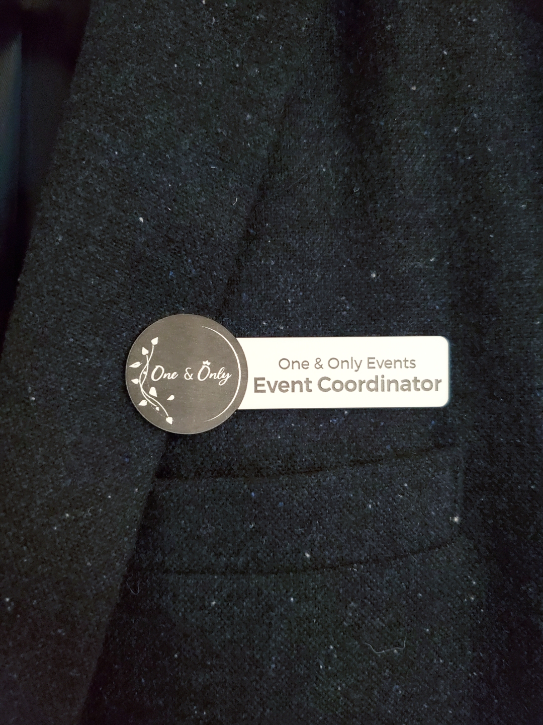 Name tag pinned on black fabric: One & Only Events Event Coordinator