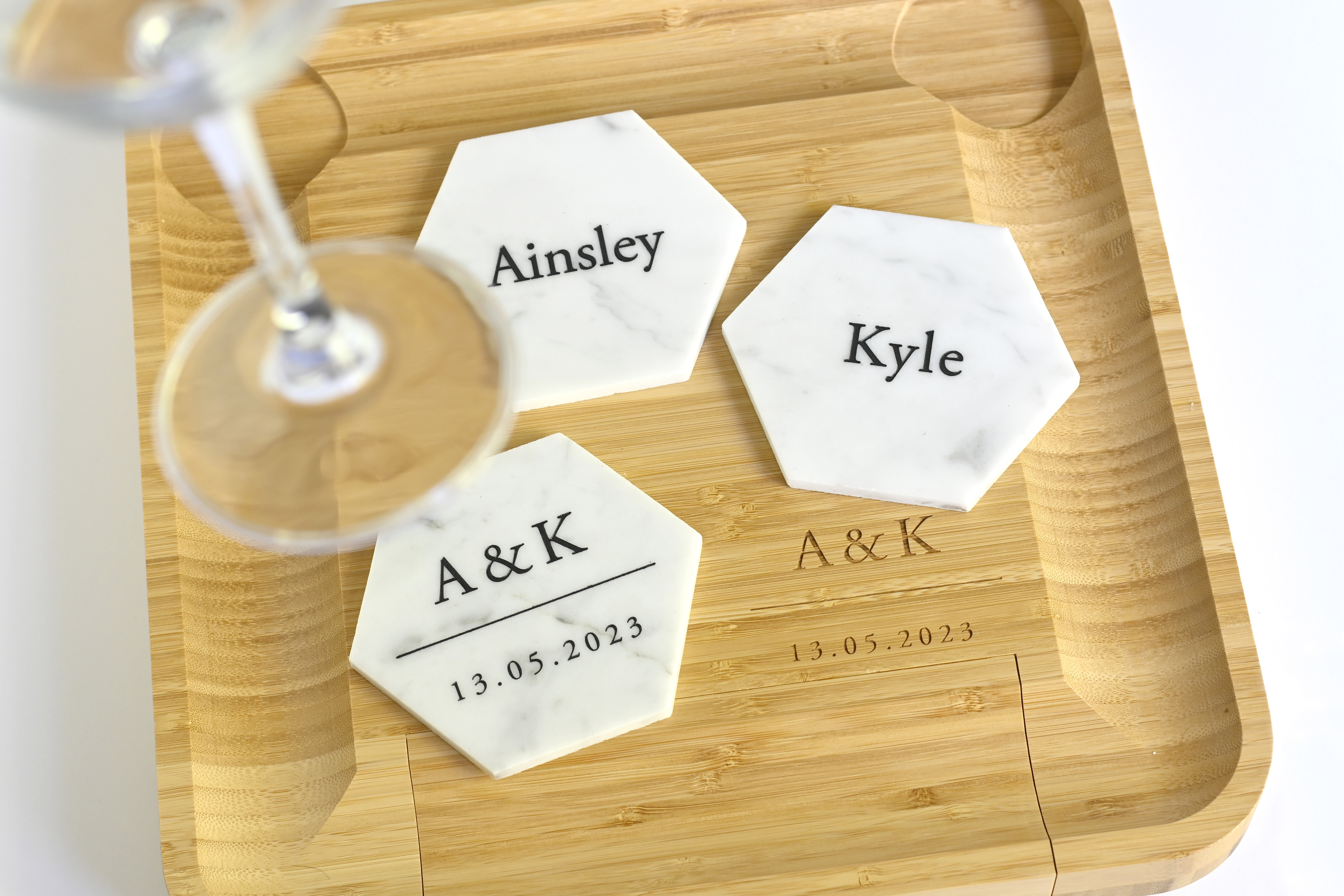 Hexagonal marble coasters with names Ainsley, Kyle, and initials A&K with date 13.05.2023 on bamboo tray