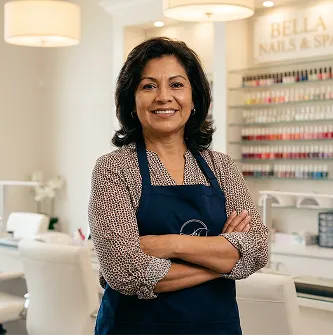 Mujer sonriente con delantal azul en un salón de uñas profesional con estantes de esmaltes.