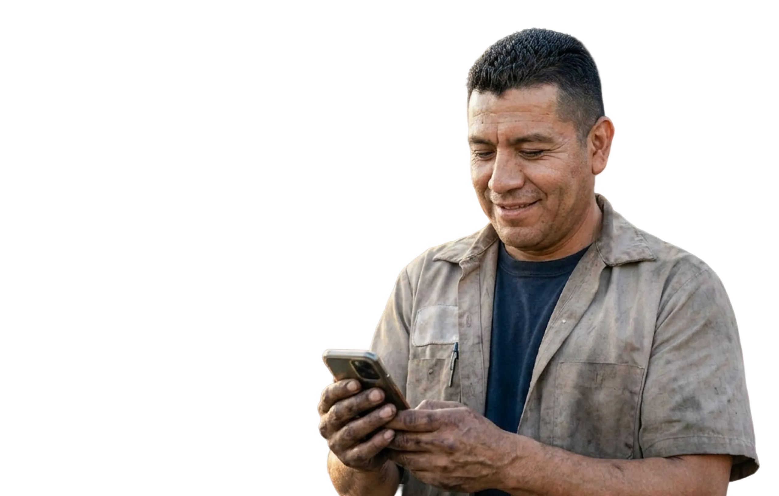 Hombre con ropa de trabajo sucia mirando y usando un teléfono móvil sonriendo.
