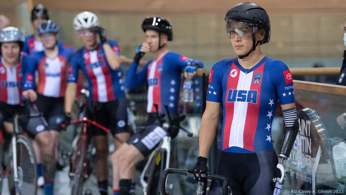 Katie Walker in Team USA cycling kit on the track with other athletes.