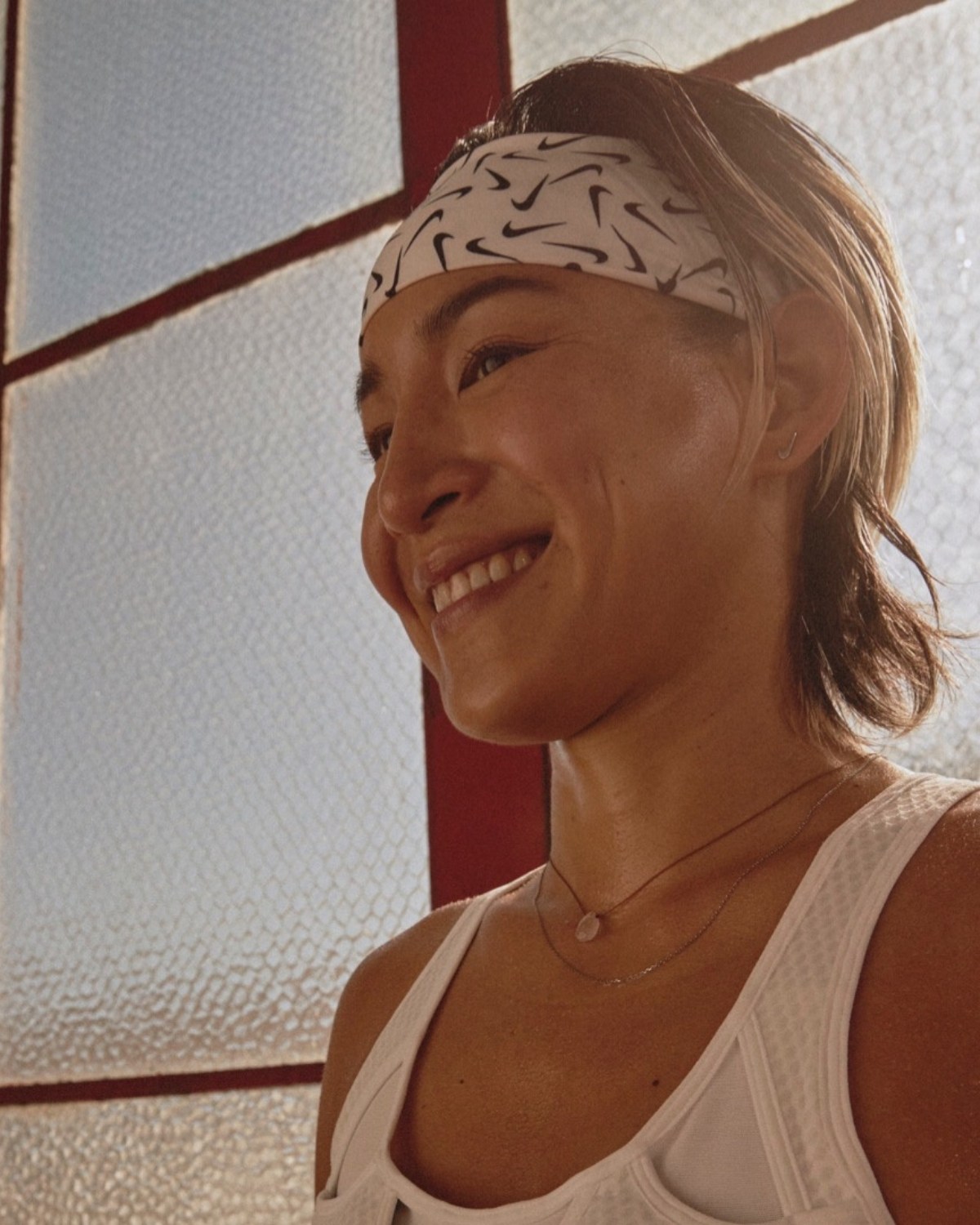 Katie Walker smiling in athletic wear near a window.