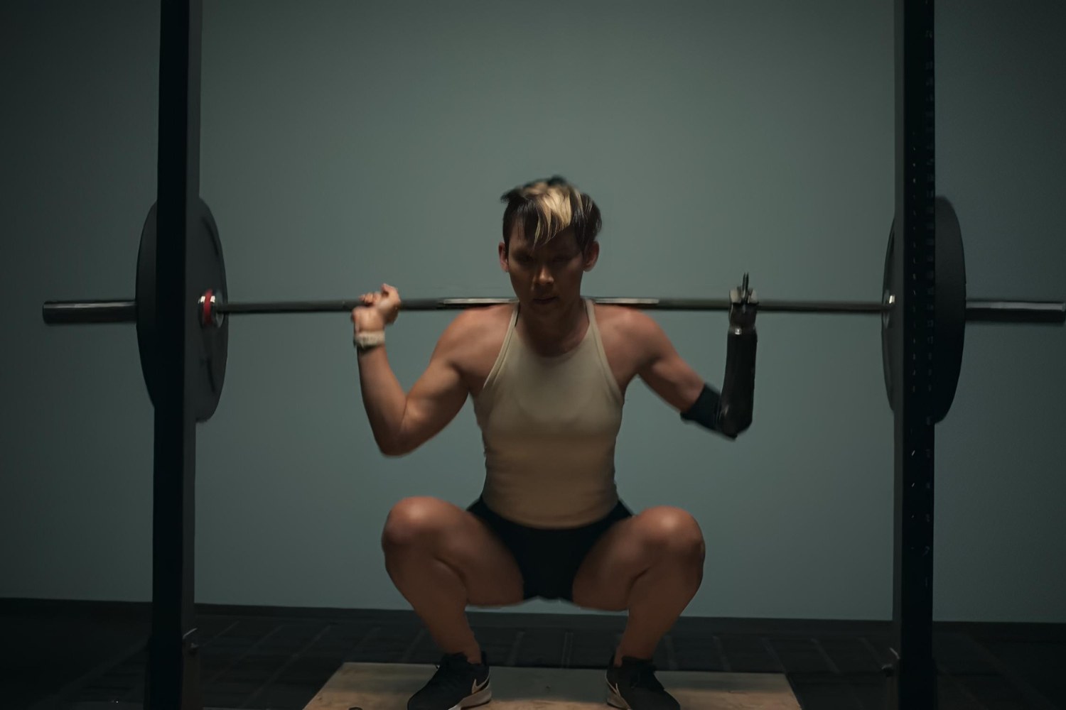 Katie Walker strength training squats with a barbell in the gym.
