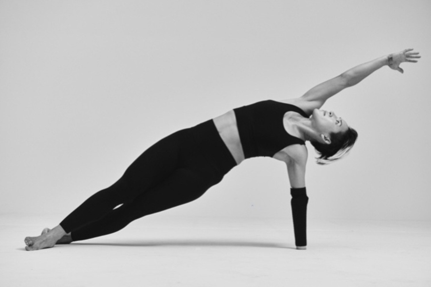 Katie Walker holding a side plank mobility yoga pose in a studio setting.