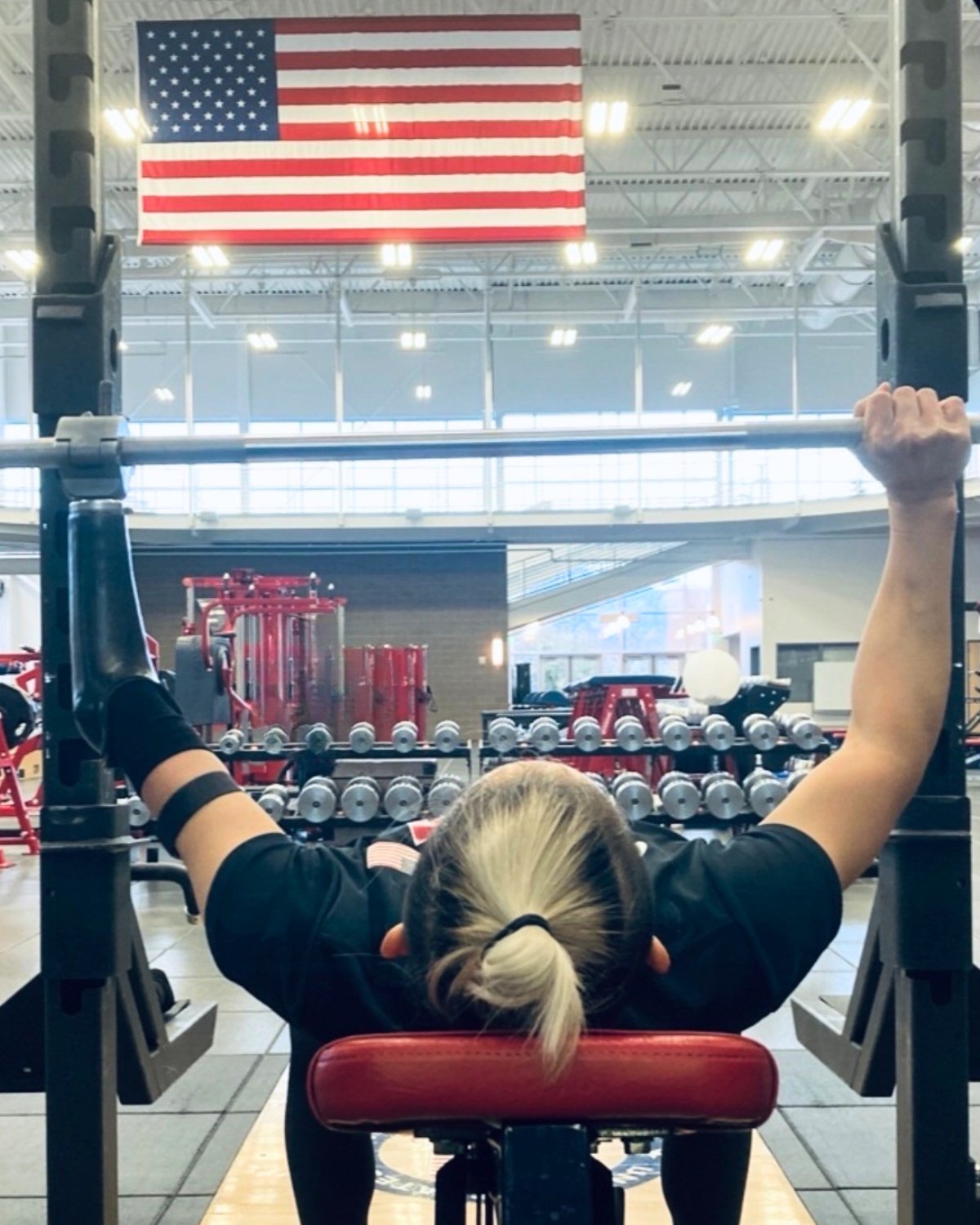 Katie Walker strength training squats with a barbell in the gym.