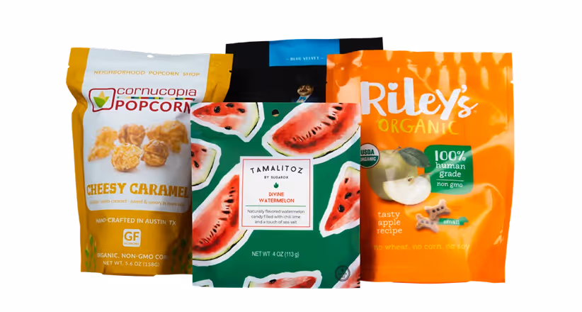 Four colorful snack bags including Cornucopia popcorn, Tamalitoz watermelon candies, and Riley's organic apple treats.