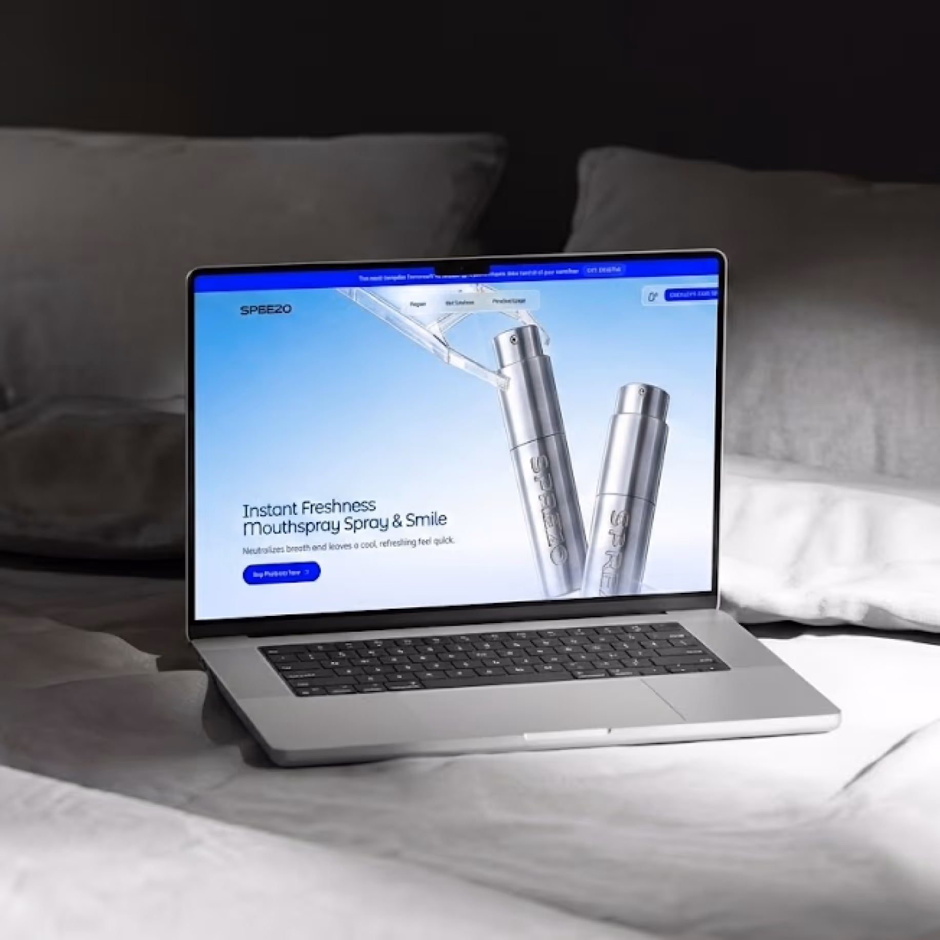 Laptop on bed showing website advertising instant freshness mouthspray spray with silver bottles.