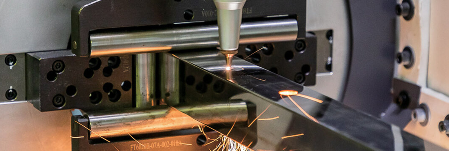 Laser cutting a piece of polished metal, emitting sparks in an industrial setting.