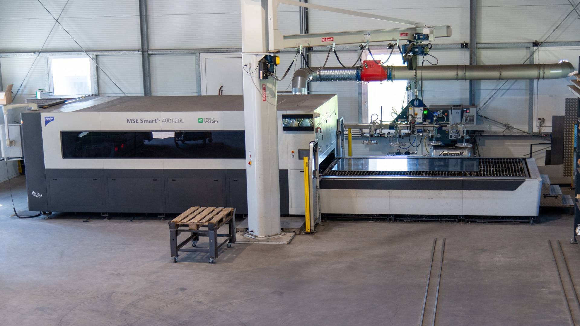 Large industrial MSE Smart FL 4001.20L machine inside a factory with a small wooden pallet on wheels nearby.