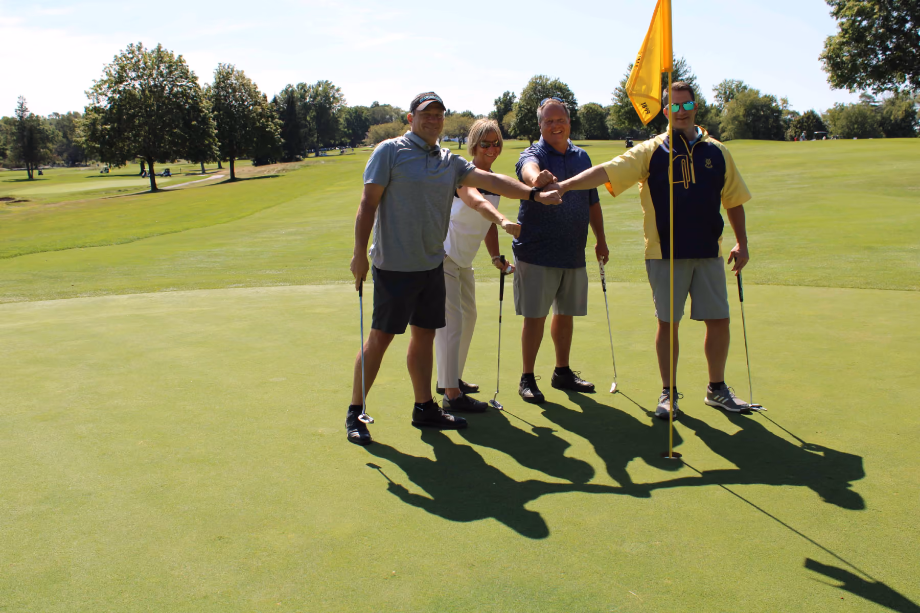 Kelser Corporation IT team members celebrating on golf course green during charity fundraiser event