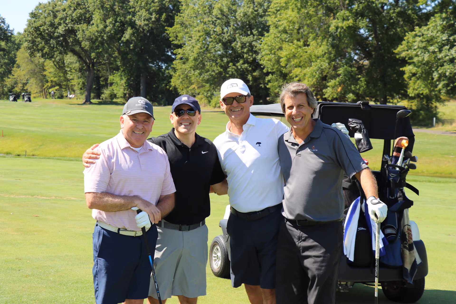 Four Kelser Corporation team members smiling together on a golf course during a company networking event