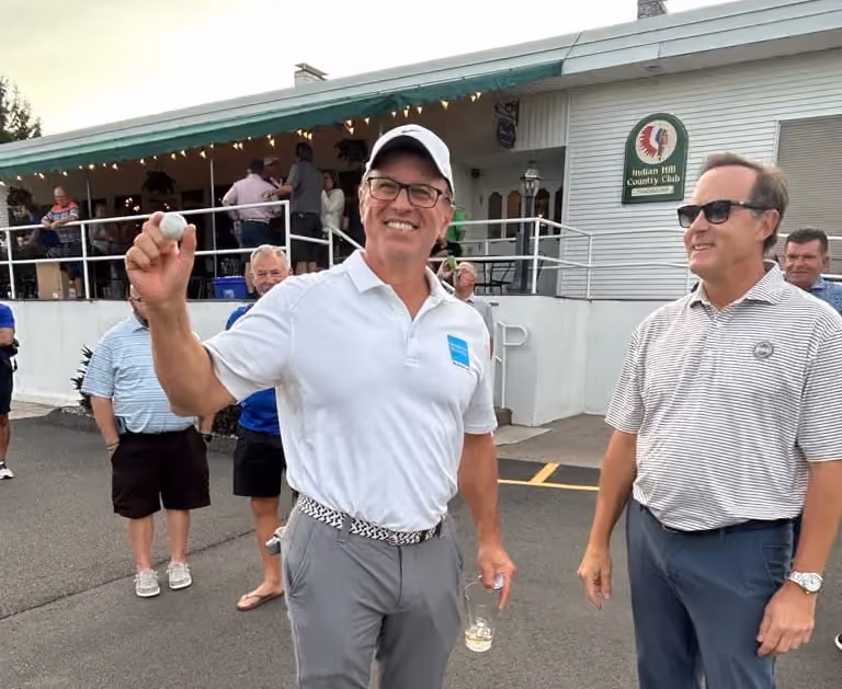 Kelser Corporation team member holding golf ball at Indian Hill Country Club charity networking event
