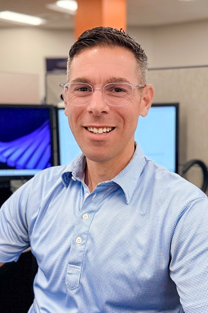 Kelser Corporation IT support professional smiling in modern managed services office with computer monitors