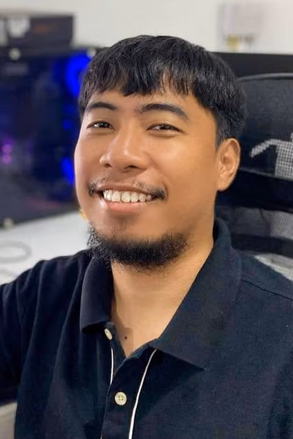 Smiling IT professional seated at a gaming chair in front of a PC workstation with RGB lighting