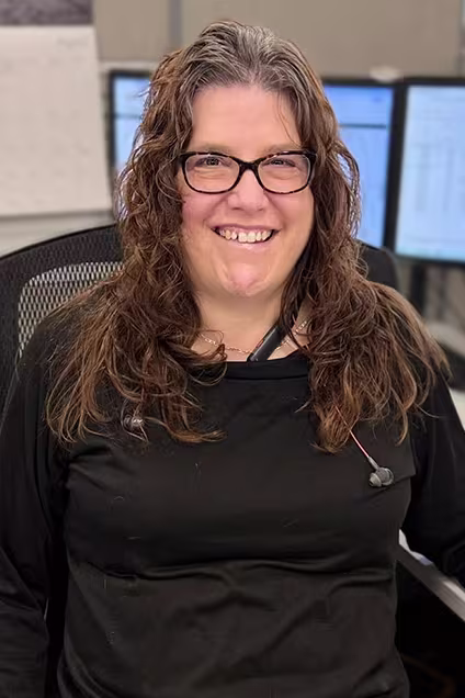 Kelser Corporation IT support specialist smiling at office workstation with multiple monitors