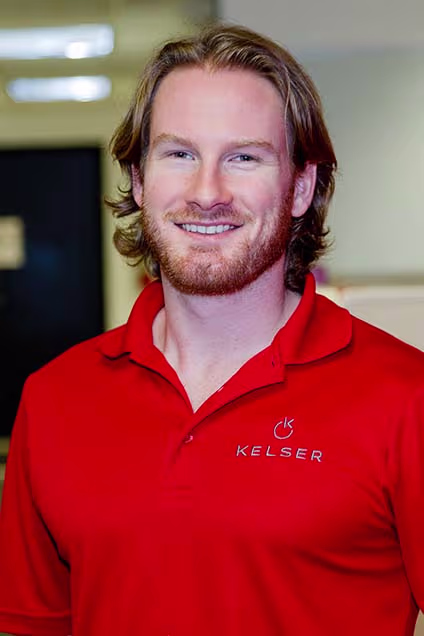 Kelser Corporation IT professional smiling in red branded polo shirt