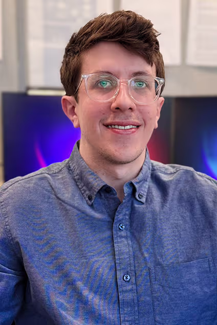 Kelser Corporation IT professional smiling in office setting with technology displays in background