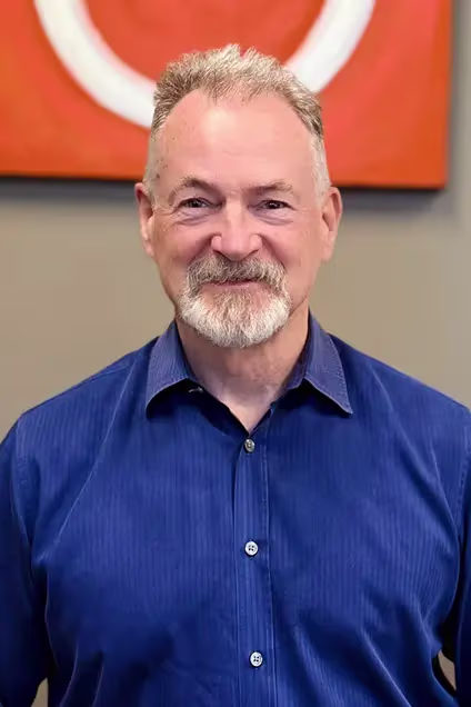 Kelser Corporation IT professional smiling in blue shirt, orange branded background
