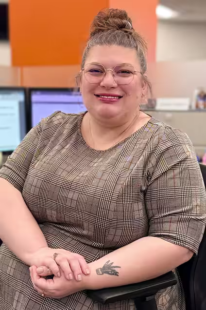 Kelser Corporation IT support team member smiling at office workstation with computer monitors