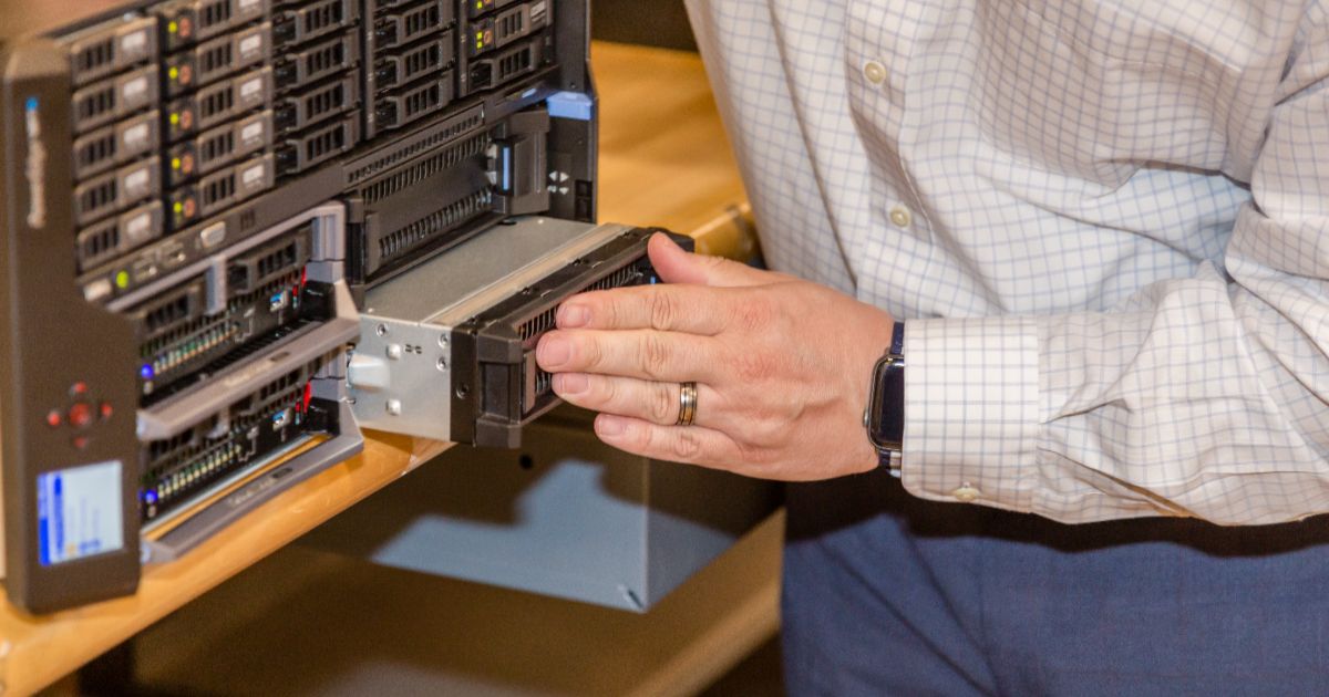 IT technician installing a hot-swap hard drive into a Dell rack-mounted server in a data center