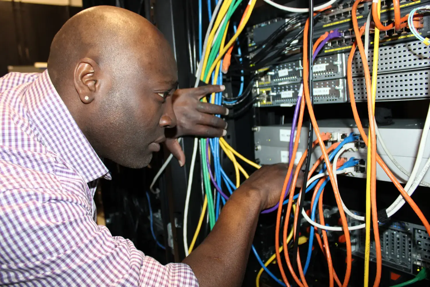 IT technician managing network cables in a server rack during hands-on infrastructure support and maintenance