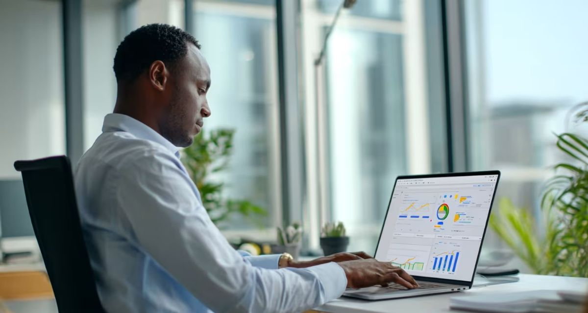 Business professional reviewing IT analytics dashboard on laptop in modern office with city view