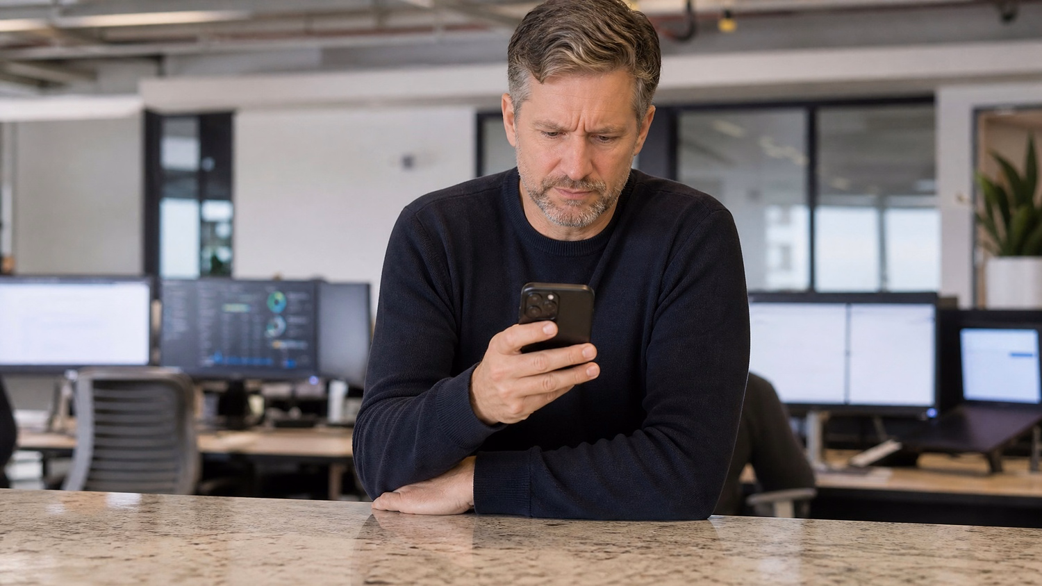 Man at office counter examines suspicious email on phone