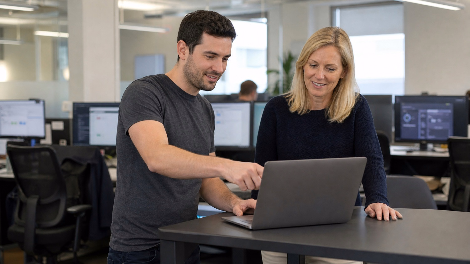 Business professionals review laptop at standing table
