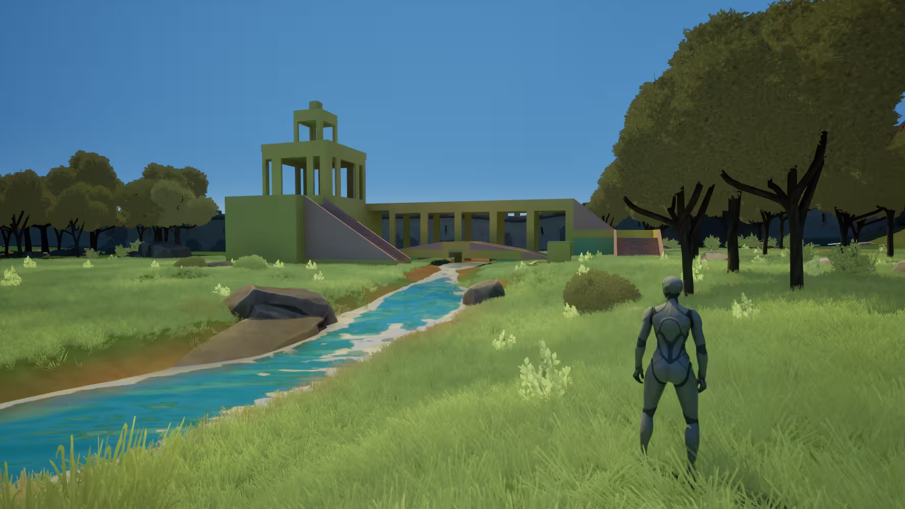 A person stands on grass by a flowing stream with trees and a large green structure in the background.
