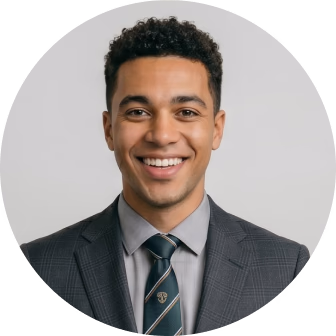 Professional headshot of a smiling man in a dark plaid blazer and striped tie against a gray background