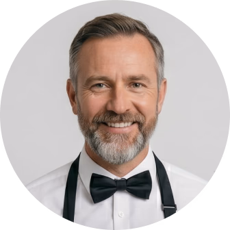 Professional headshot of a man with beard wearing formal tuxedo with bow tie against gray background