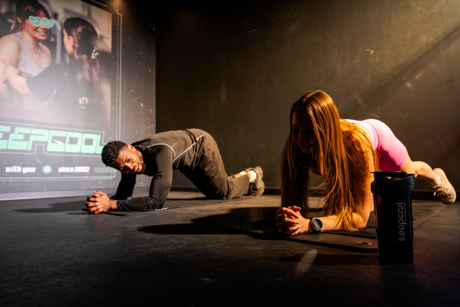 Deux athlètes en position de gainage sur scène, cours fitness intensif Keepcool.
