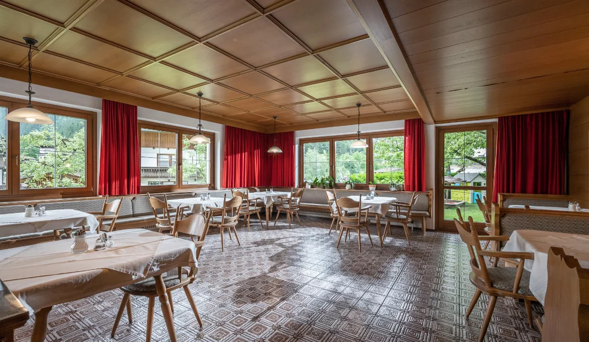 Kumbichlhof wooden-ceiling dining room with red benches at the Mayrhofen farmhouse.
