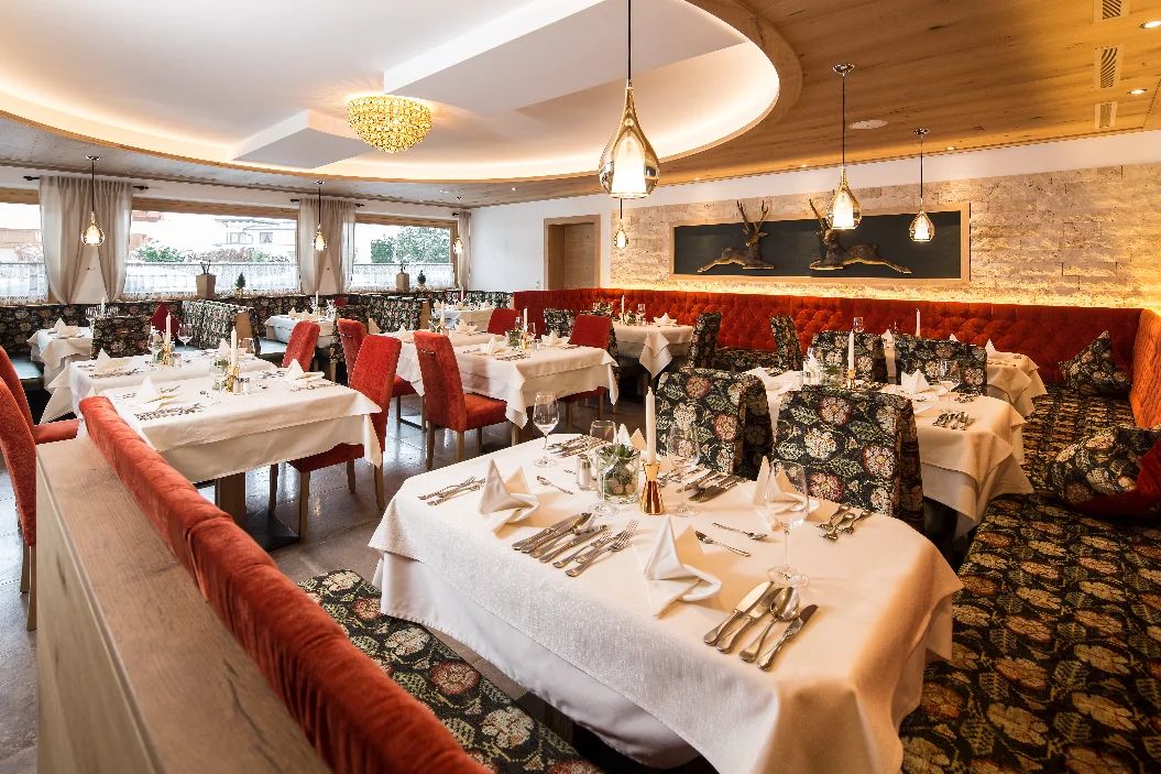 Jägerhof elegant dining room with red benches at the Mayrhofen three-star hotel.