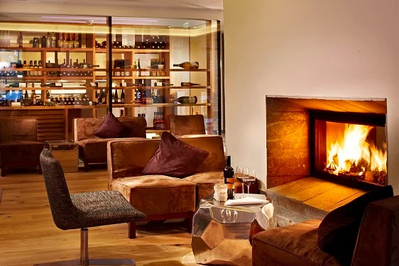 Huber's Boutique cozy fireplace lounge with wine shelves at the Mayrhofen boutique hotel.