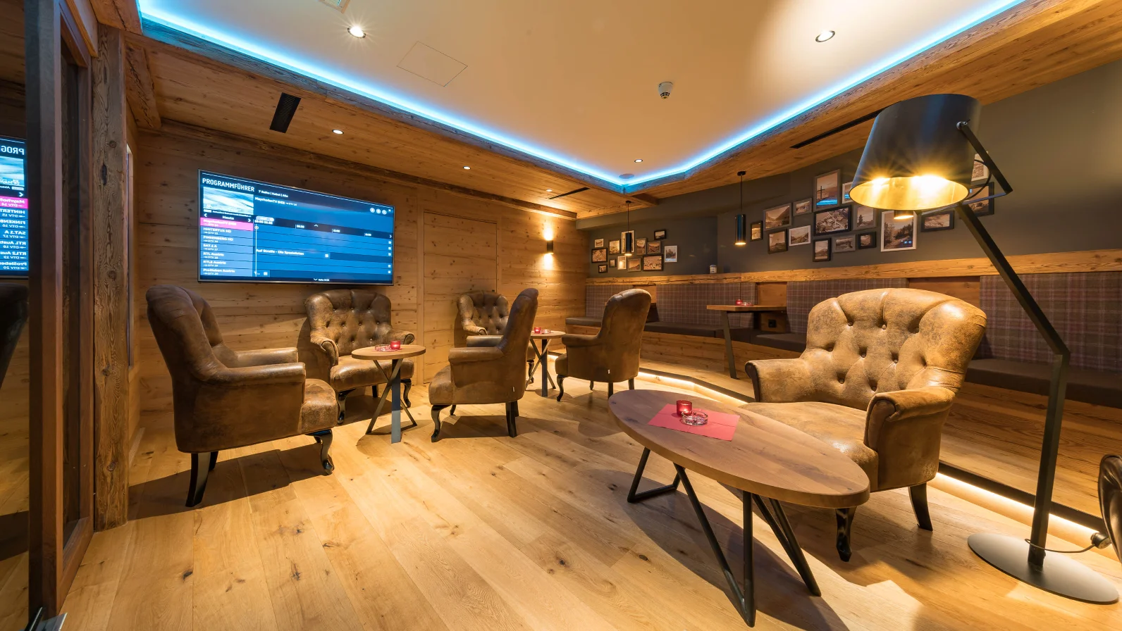 Berghof wooden lounge with TV and chairs at the Mayrhofen four-star hotel.