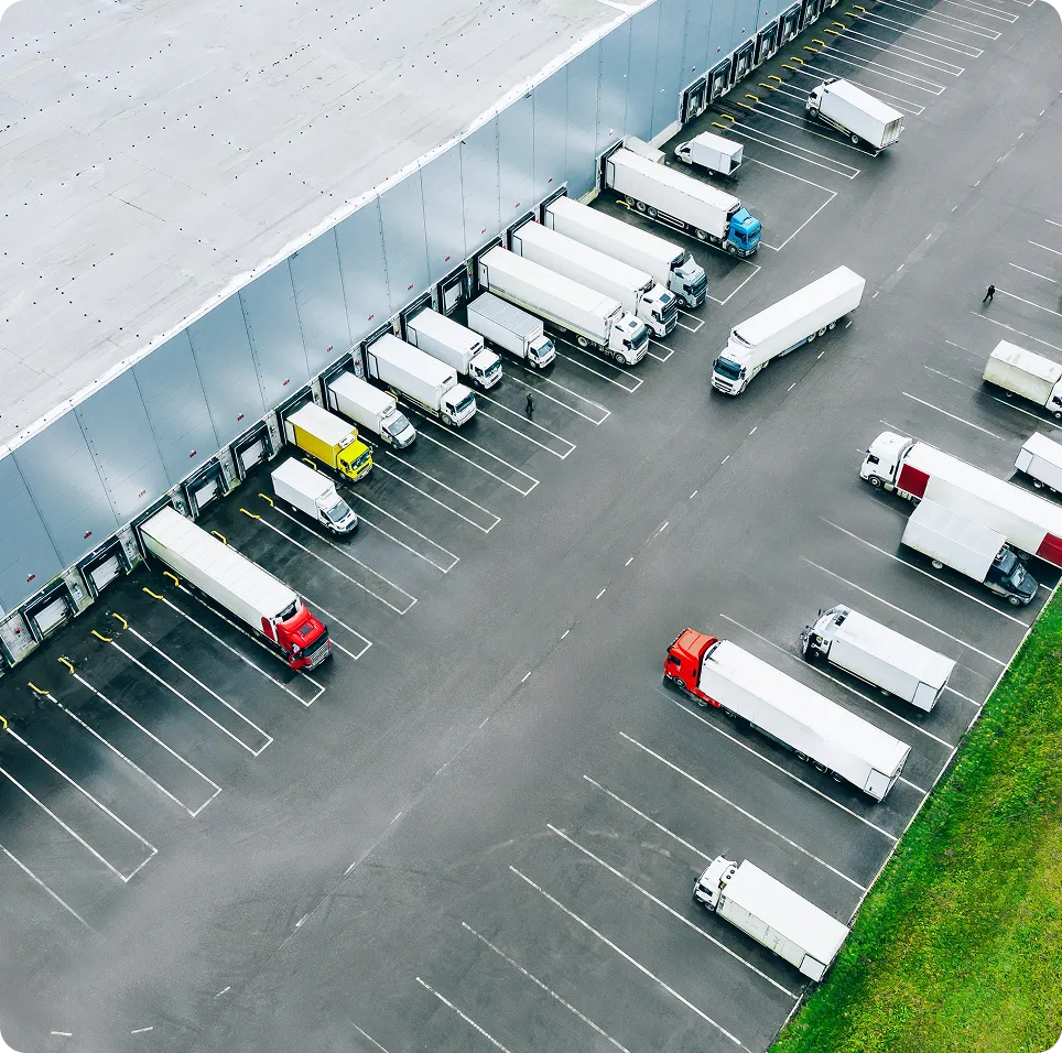 Aerial view of multiple trucks parked at loading docks attached to a large warehouse building.