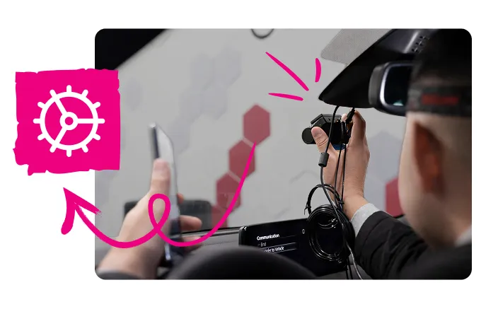 Person wearing a VR headset holding a small camera device inside a vehicle.