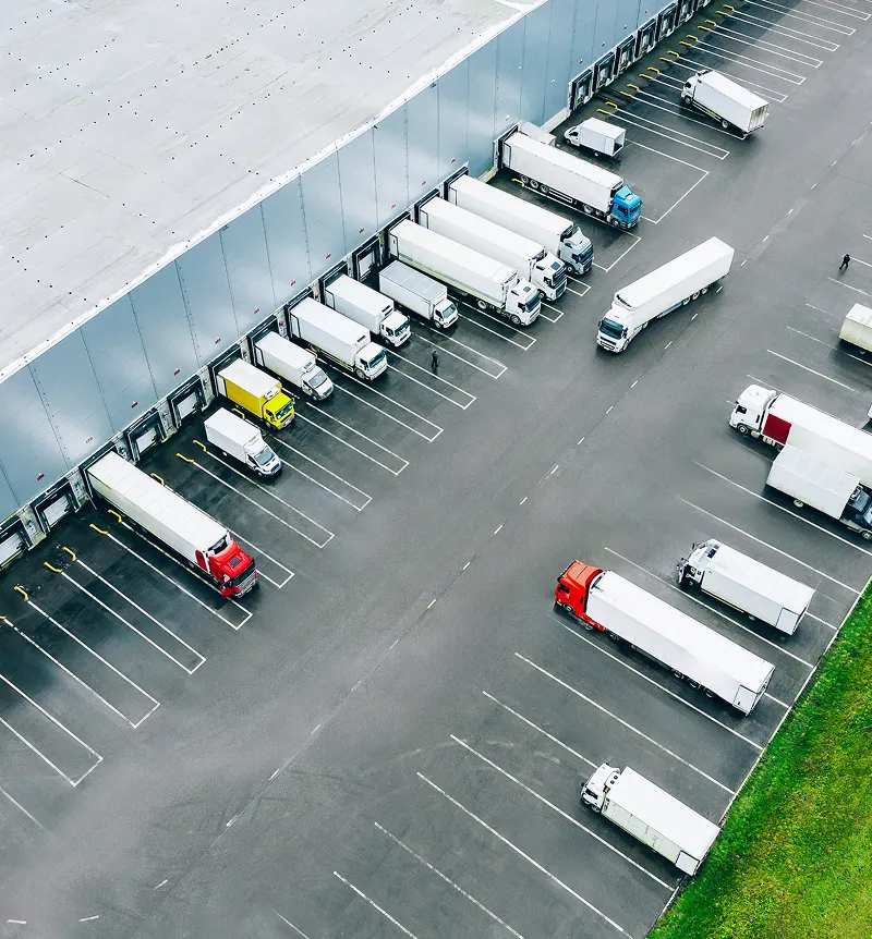 Aerial view of trucks lined up in loading bays at a large warehouse or distribution center.