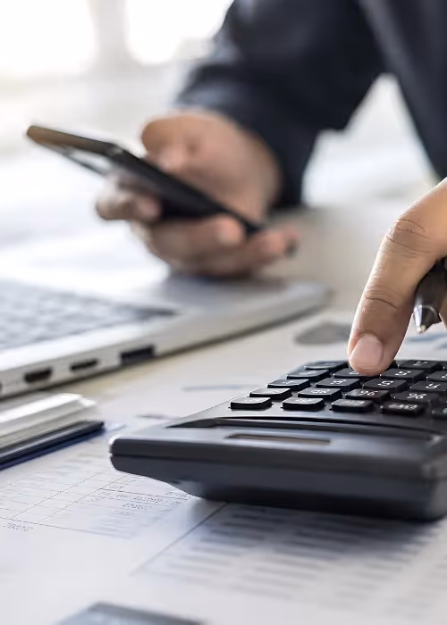 Person using a calculator and looking at paperwork