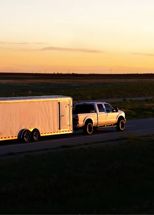 Car towing trailer down road