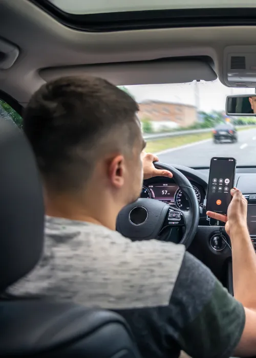Man looking at his phone whilst driving