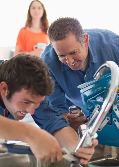 Plumbers in overalls repairing a broken sink