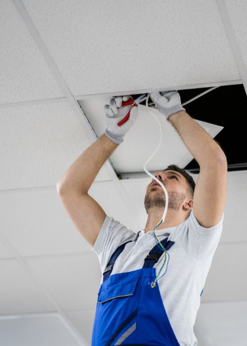 Electrician fixing wiring in the ceiling of a building