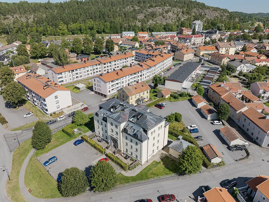 Flygfoto över Folkskolans bostadsområde med lägenheter och parkeringsplatser i bakgrunden.