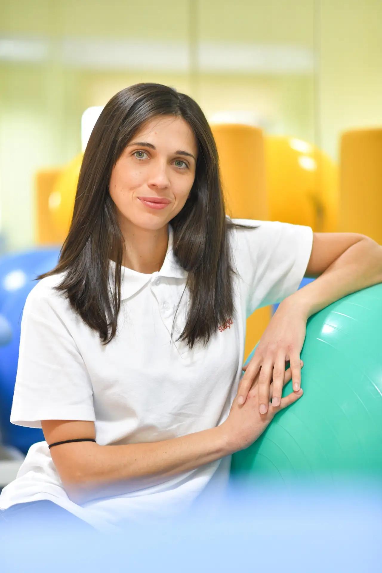 Young woman resting against an exercise ball in the therapy gym