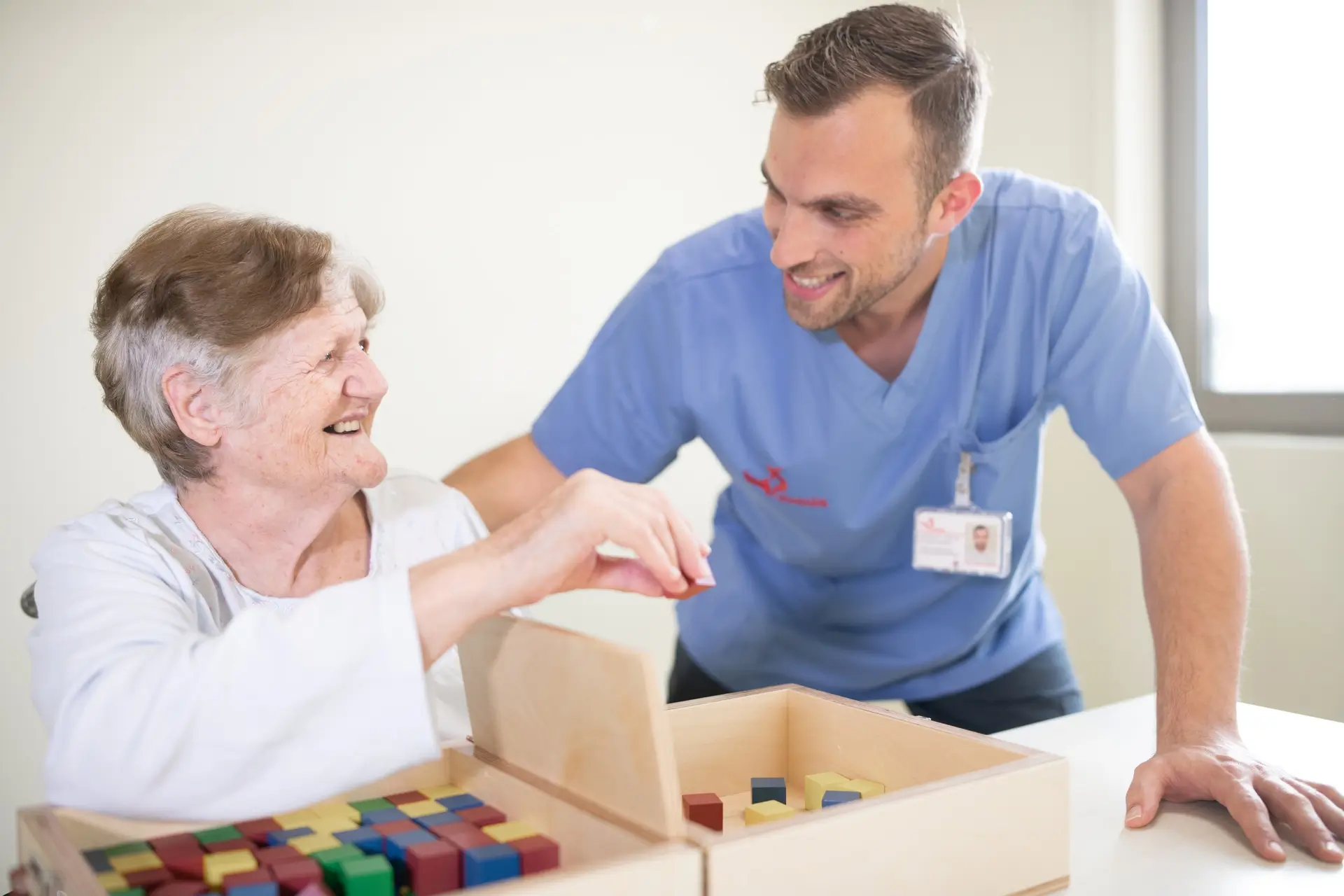 Therapist and an older woman smiling at each other during a table-top session