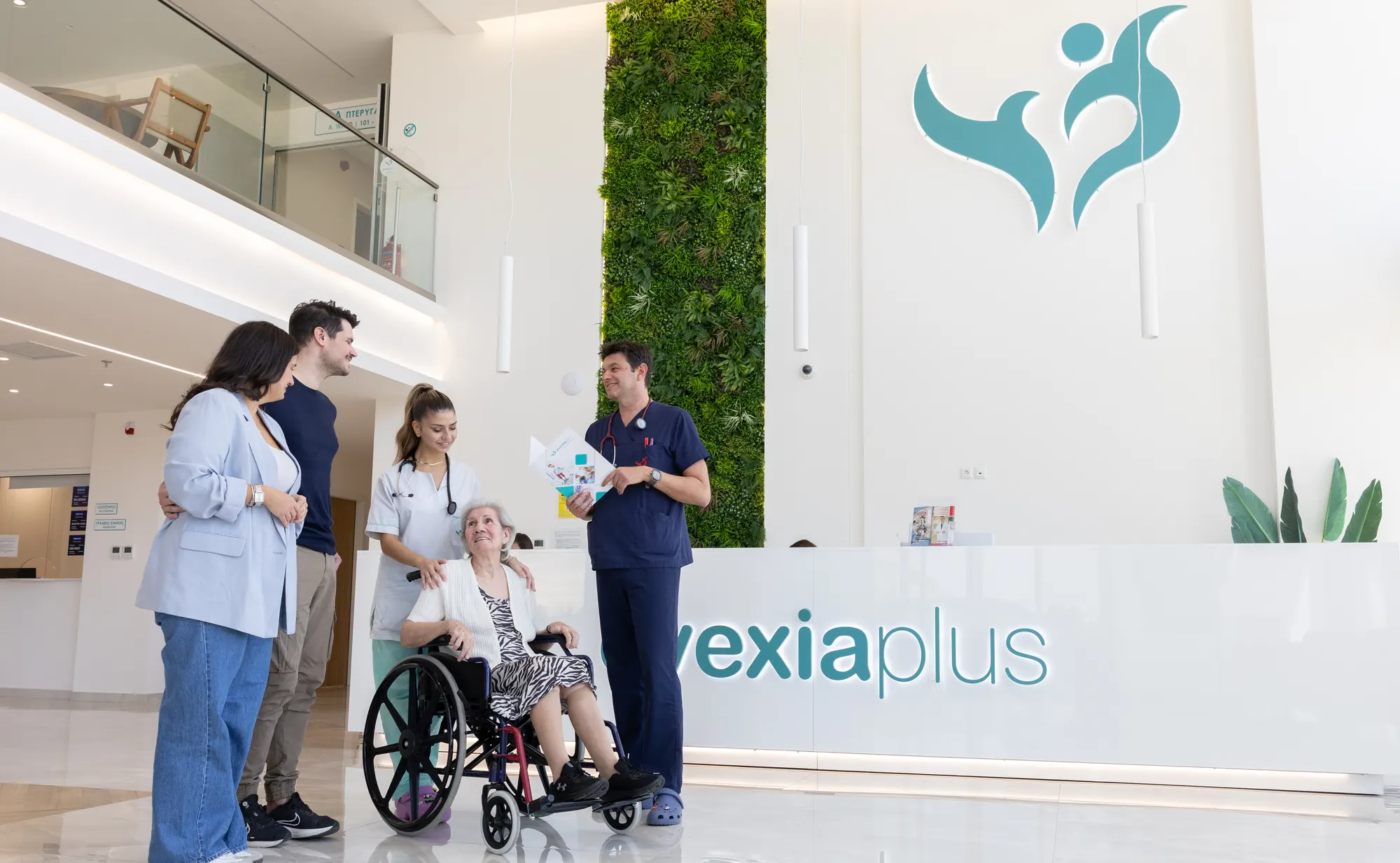 A Health Advisor talking a family and a patient in a wheelchair through a brochure at the Evexia Plus reception