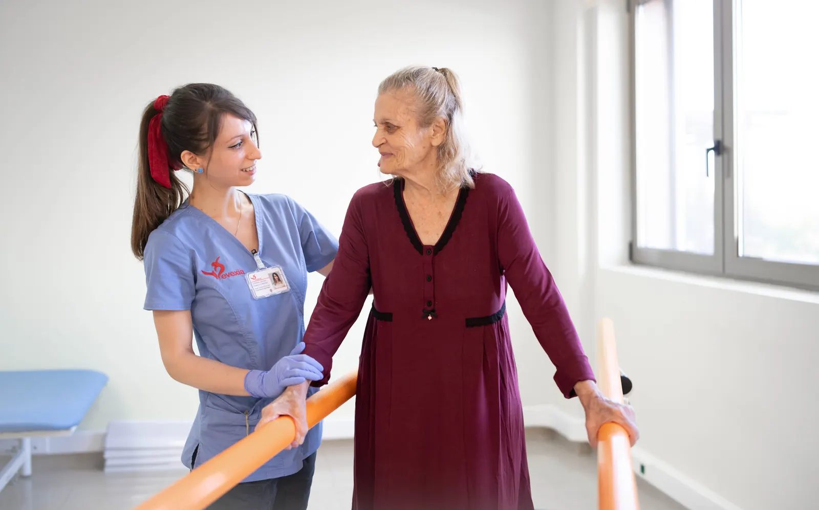 Therapist supporting a woman at the parallel bars